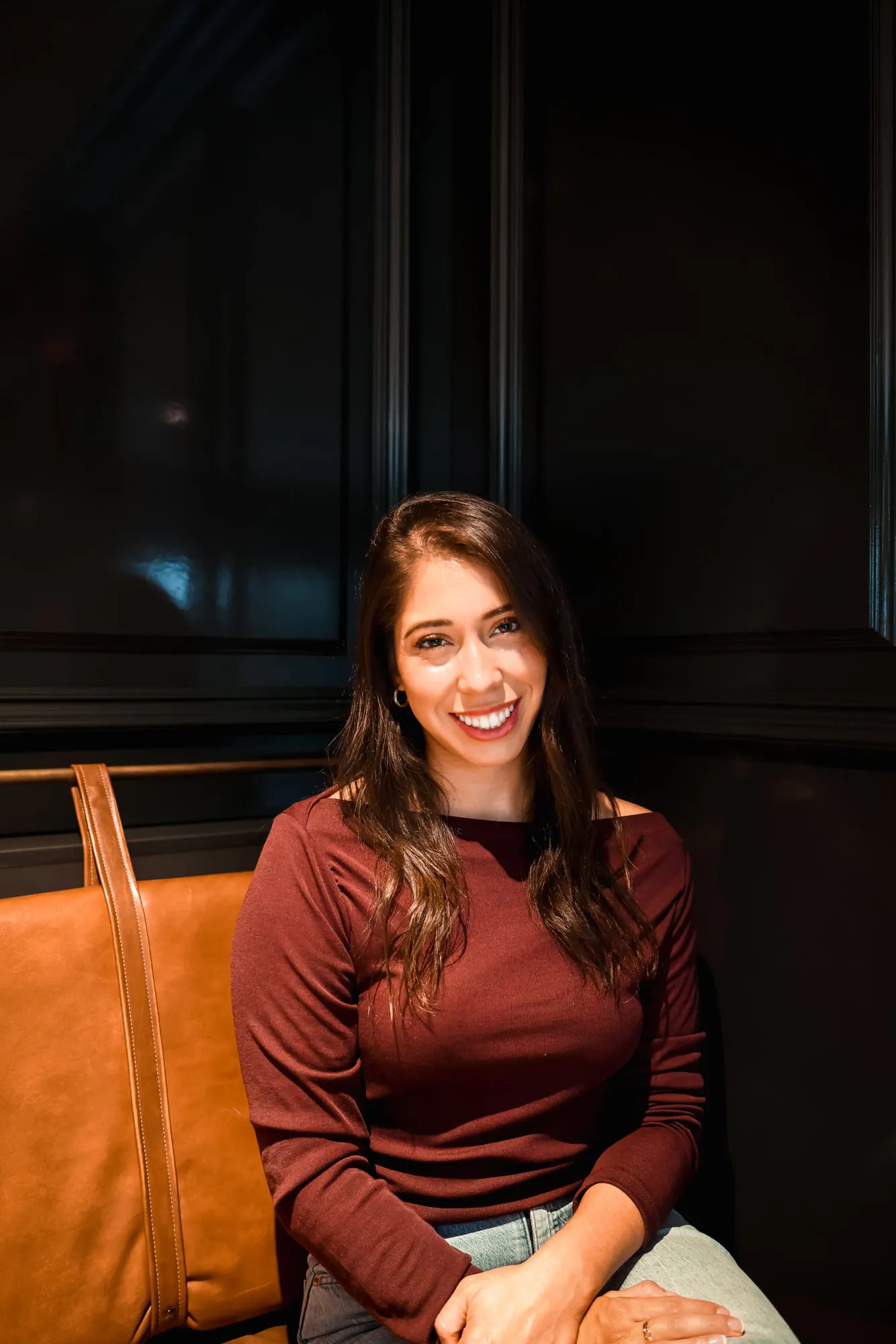 Lacey Villaseñor smiling, seated in a leather booth against dark wood panels