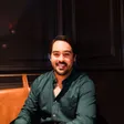 Mauri Villaseñor smiling, seated at a table in a leather booth against dark wood panels